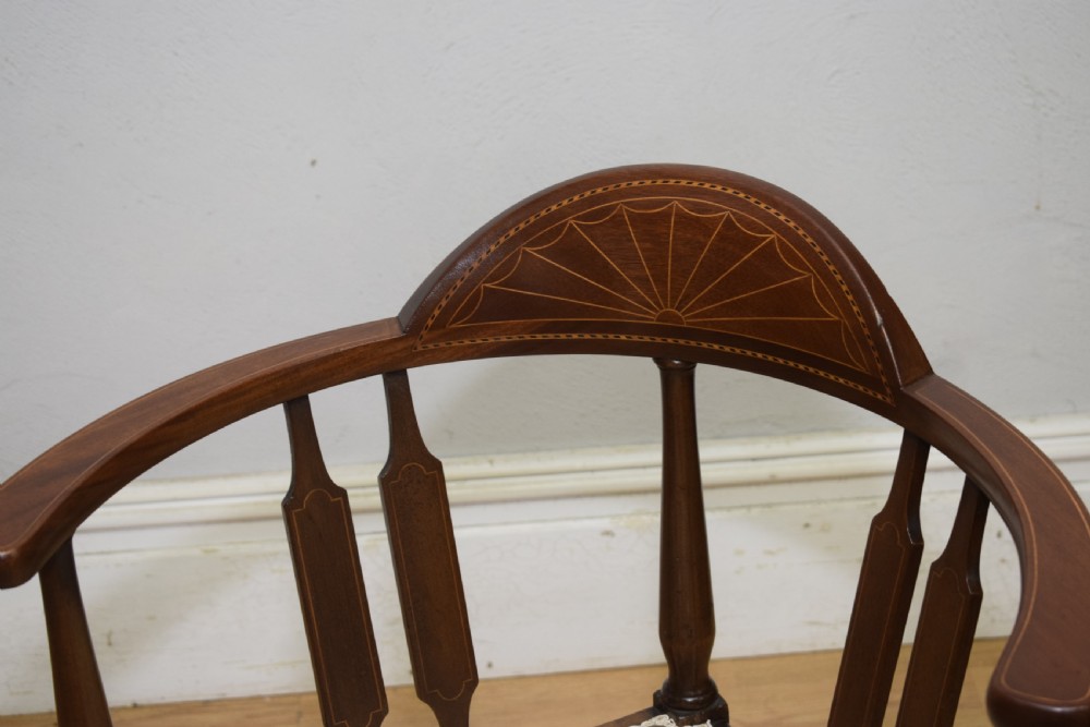 An Edwardian mahogany corner chair featuring a curved top rail with fan inlay, turned spindles, and a floral upholstered square seat. View VII