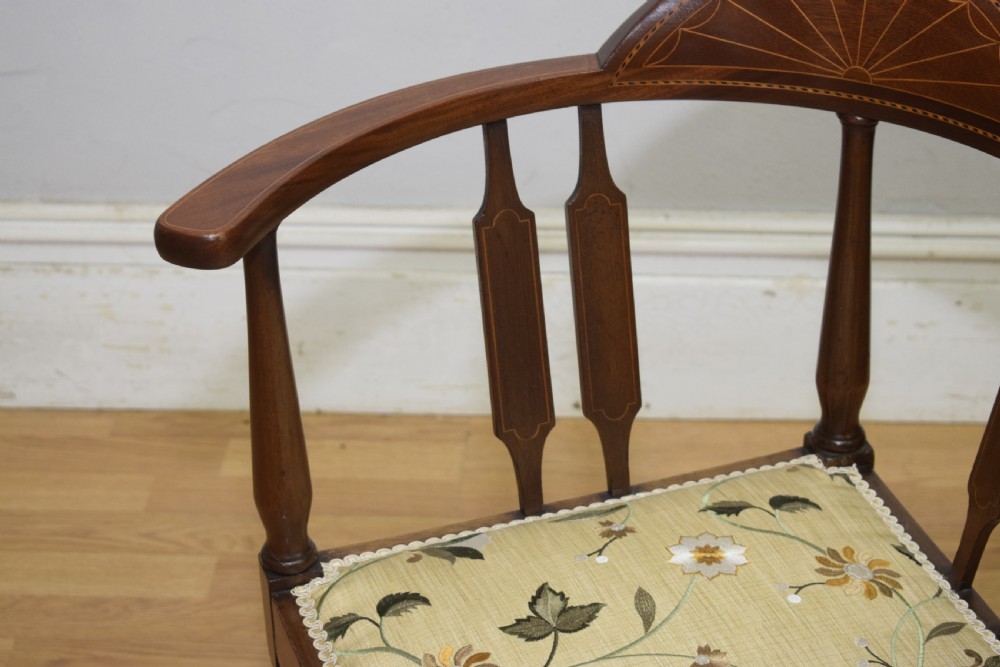 An Edwardian mahogany corner chair featuring a curved top rail with fan inlay, turned spindles, and a floral upholstered square seat. View VIII