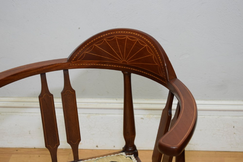 An Edwardian mahogany corner chair featuring a curved top rail with fan inlay, turned spindles, and a floral upholstered square seat. View IX
