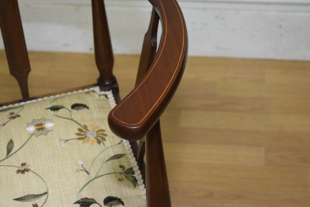 An Edwardian mahogany corner chair featuring a curved top rail with fan inlay, turned spindles, and a floral upholstered square seat. View X
