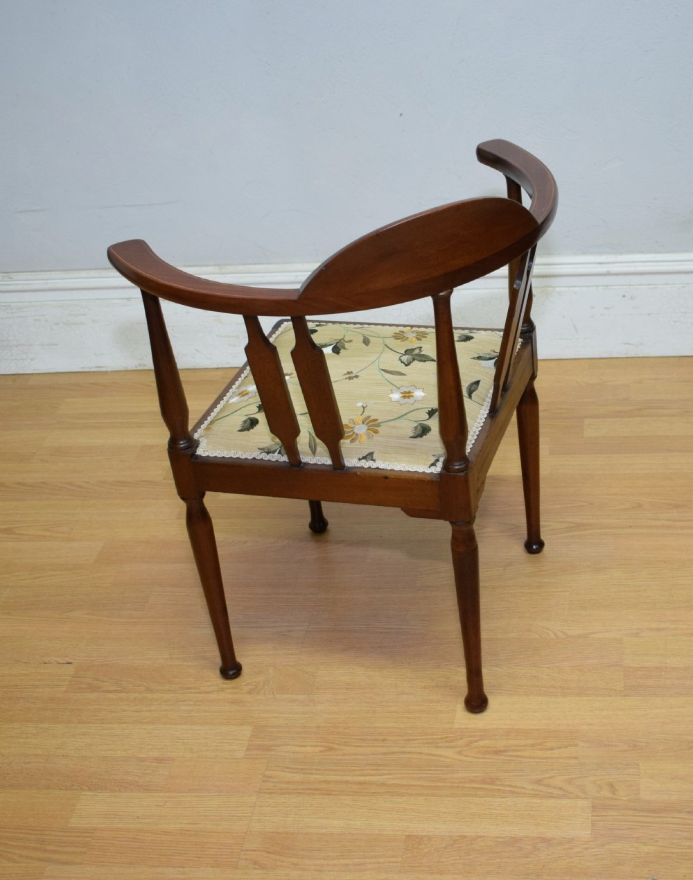 An Edwardian mahogany corner chair featuring a curved top rail with fan inlay, turned spindles, and a floral upholstered square seat. View XIII