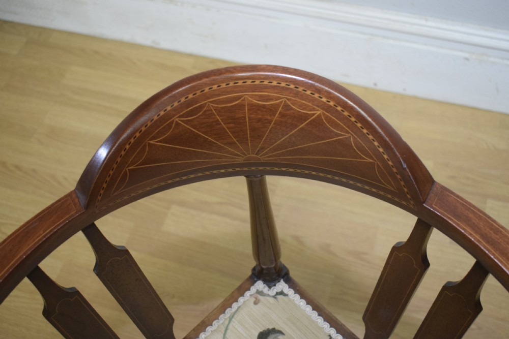 An Edwardian mahogany corner chair featuring a curved top rail with fan inlay, turned spindles, and a floral upholstered square seat. View XV