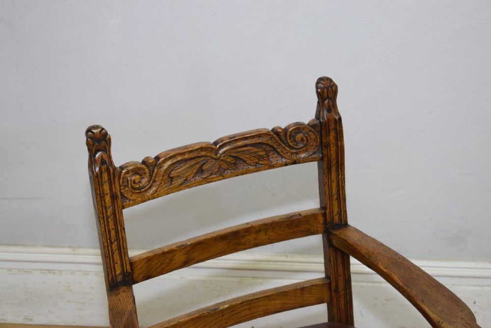 A carved oak armchair featuring a brown leather seat with stud detailing, turned front legs, and carved crest rail on the backrest. View VIII