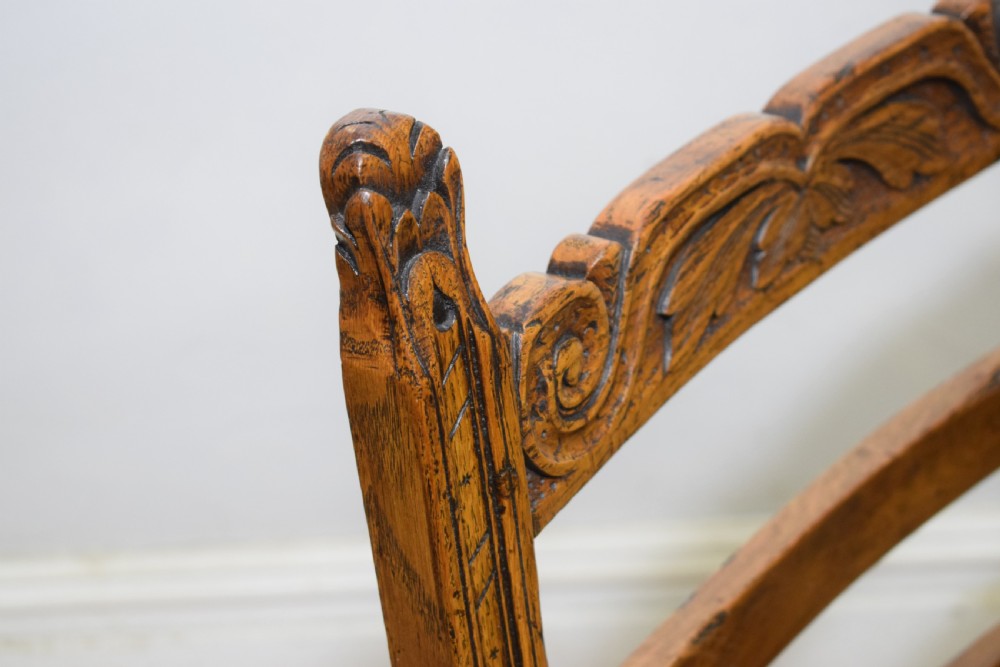 A carved oak armchair featuring a brown leather seat with stud detailing, turned front legs, and carved crest rail on the backrest. View XVII