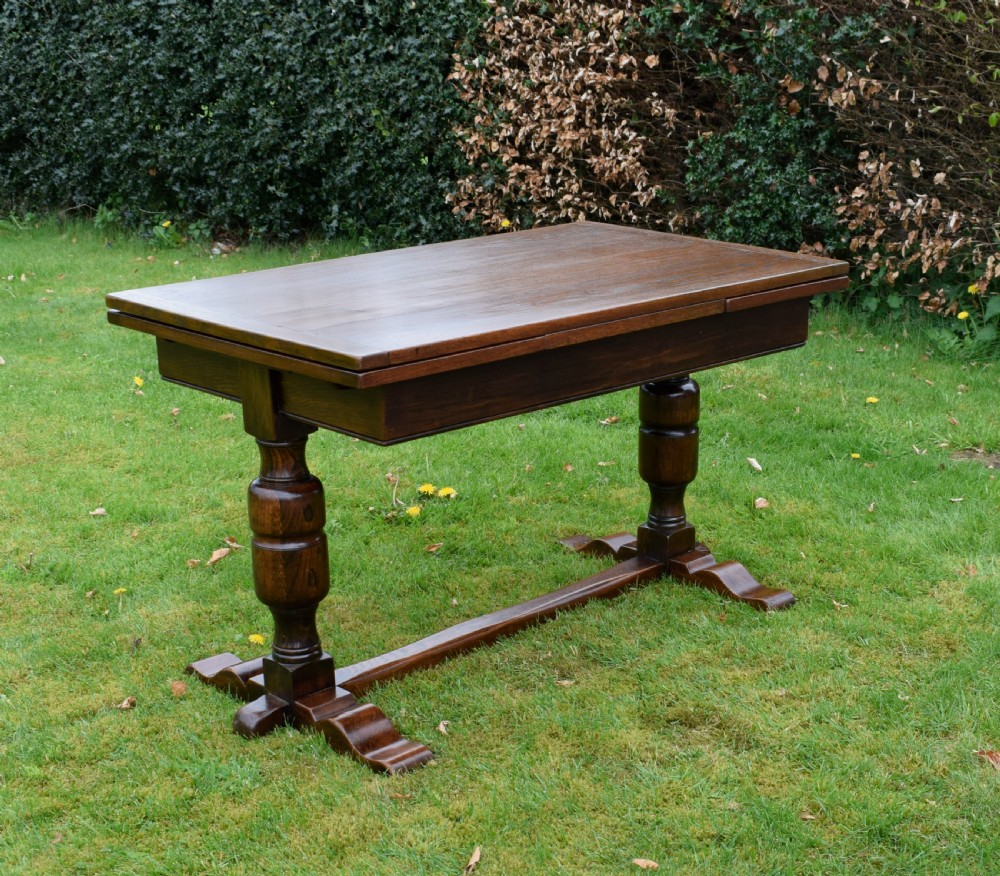 An early 20th-century dark oak refectory dining table featuring turned bulbous legs, a low central stretcher, and a rectangular wooden top.