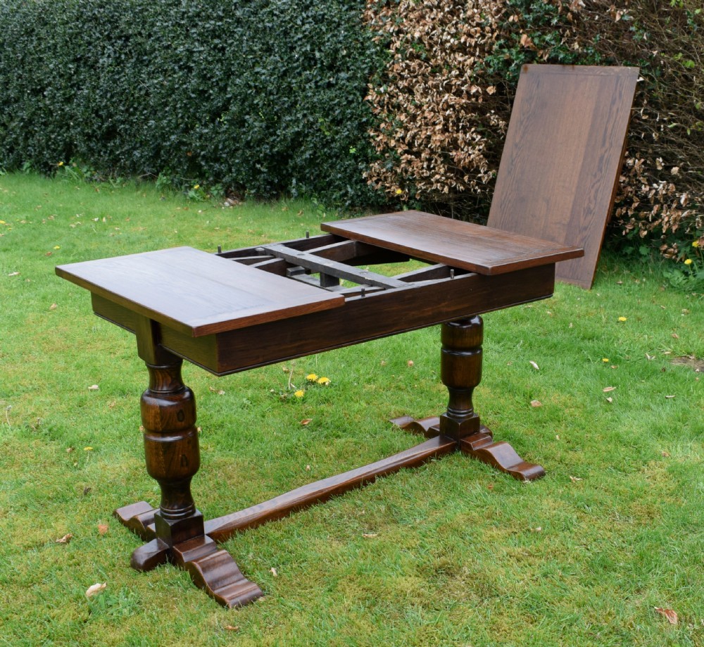 An early 20th-century dark oak refectory dining table featuring turned bulbous legs, a low central stretcher, and a rectangular wooden top. View XXII