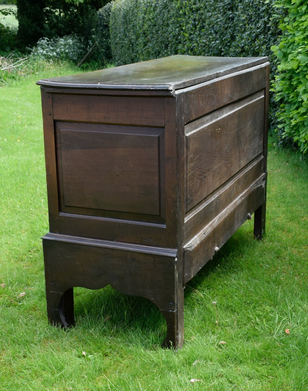 A 17th-century style dark oak court cupboard with four arched fielded panel doors over three drawers fitted with turned wooden knobs. View VII