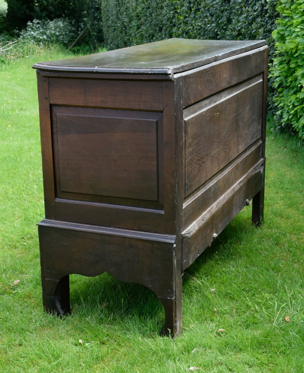 A 17th-century style dark oak court cupboard with four arched fielded panel doors over three drawers fitted with turned wooden knobs. View VIII