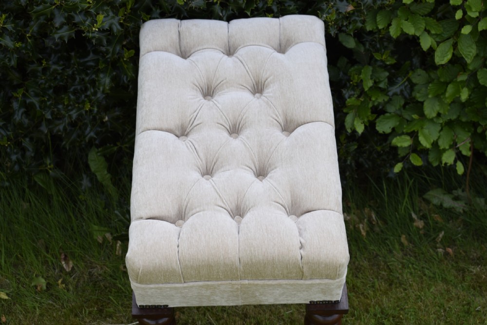 A rectangular cream fabric upholstered stool featuring deep button tufting, brass nailhead trim, and dark turned wooden legs with brass castors. View XIV