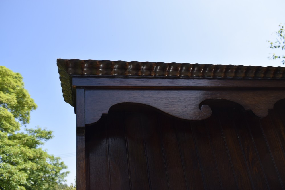 A dark oak Welsh dresser featuring an upper open plate rack with three shelves and a lower base with four drawers supported by turned legs and a bottom shelf. View VIII