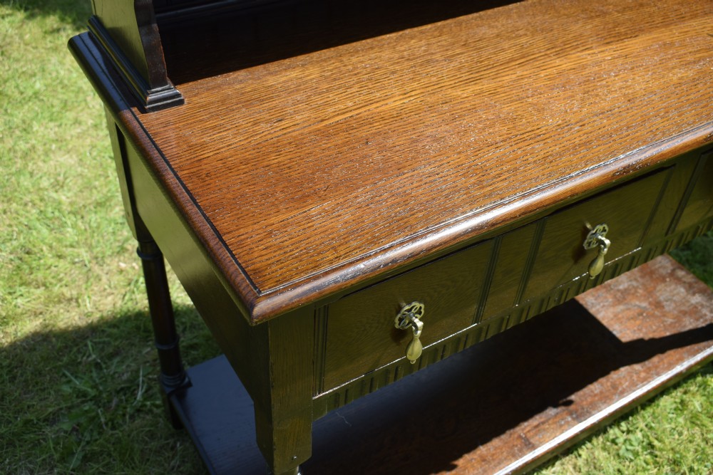 A dark oak Welsh dresser featuring an upper open plate rack with three shelves and a lower base with four drawers supported by turned legs and a bottom shelf. View XI