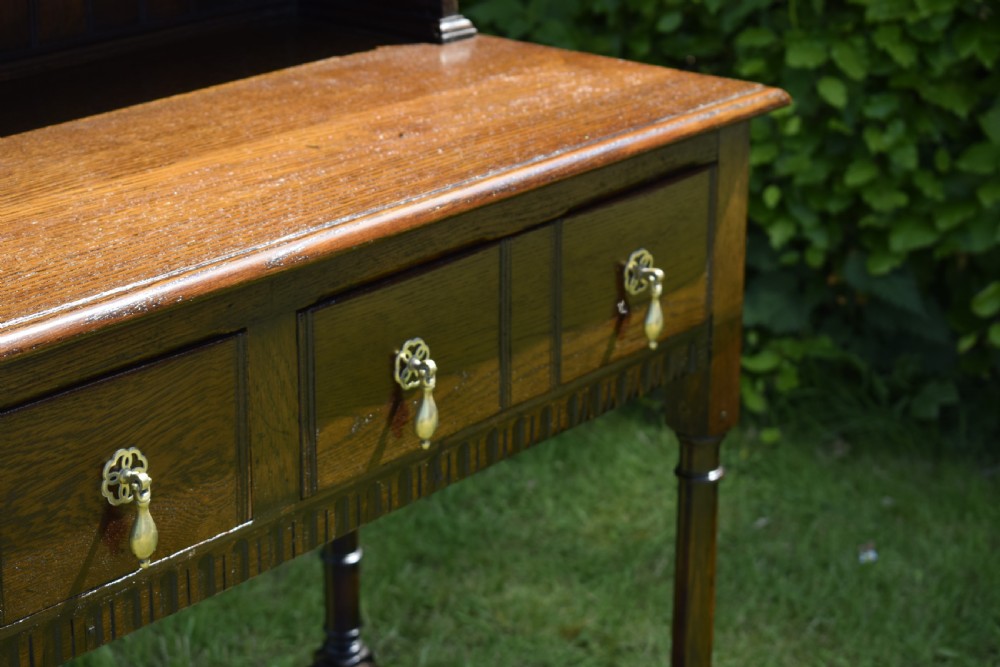 A dark oak Welsh dresser featuring an upper open plate rack with three shelves and a lower base with four drawers supported by turned legs and a bottom shelf. View XIX