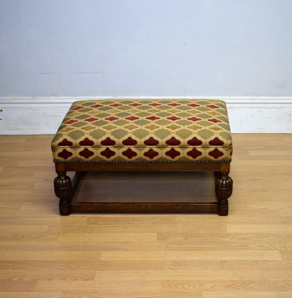 An antique carved oak stool with a geometric patterned upholstered seat, turned legs, and a perimeter wood stretcher. View II
