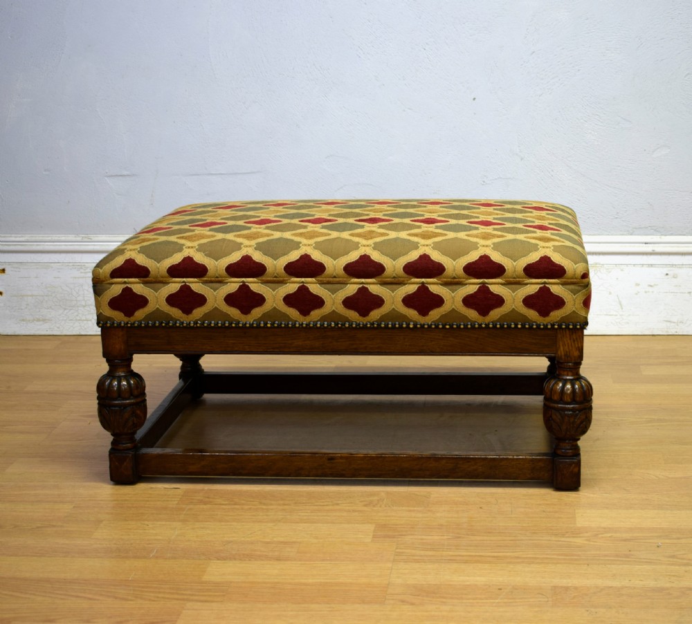 An antique carved oak stool with a geometric patterned upholstered seat, turned legs, and a perimeter wood stretcher. View III