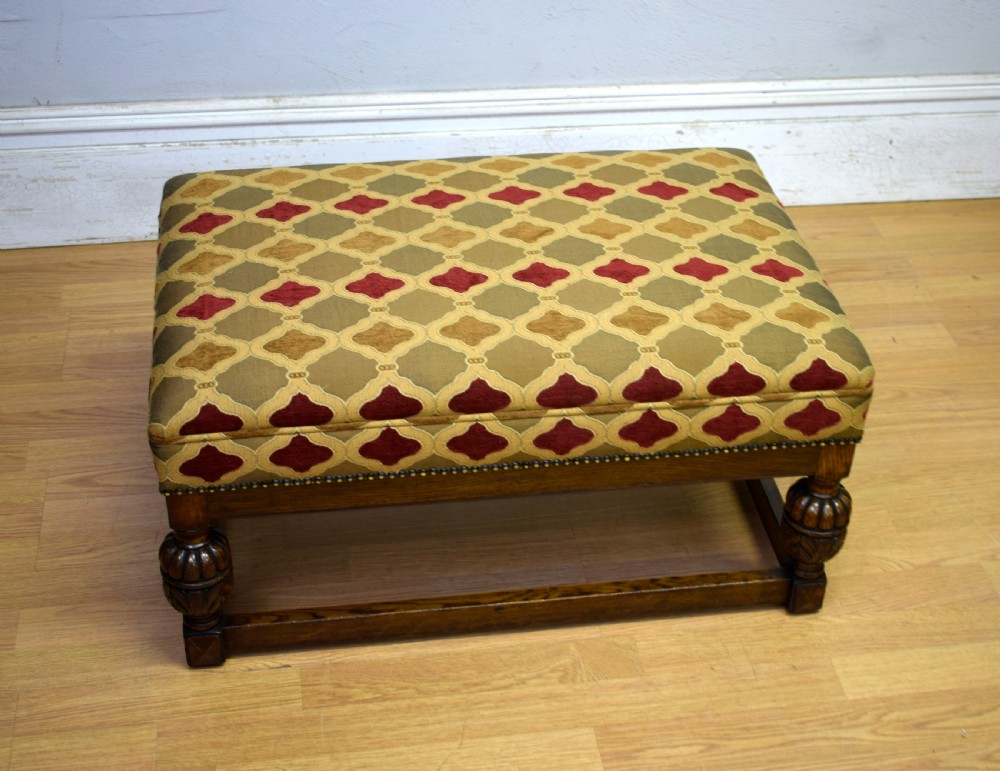 An antique carved oak stool with a geometric patterned upholstered seat, turned legs, and a perimeter wood stretcher. View VI