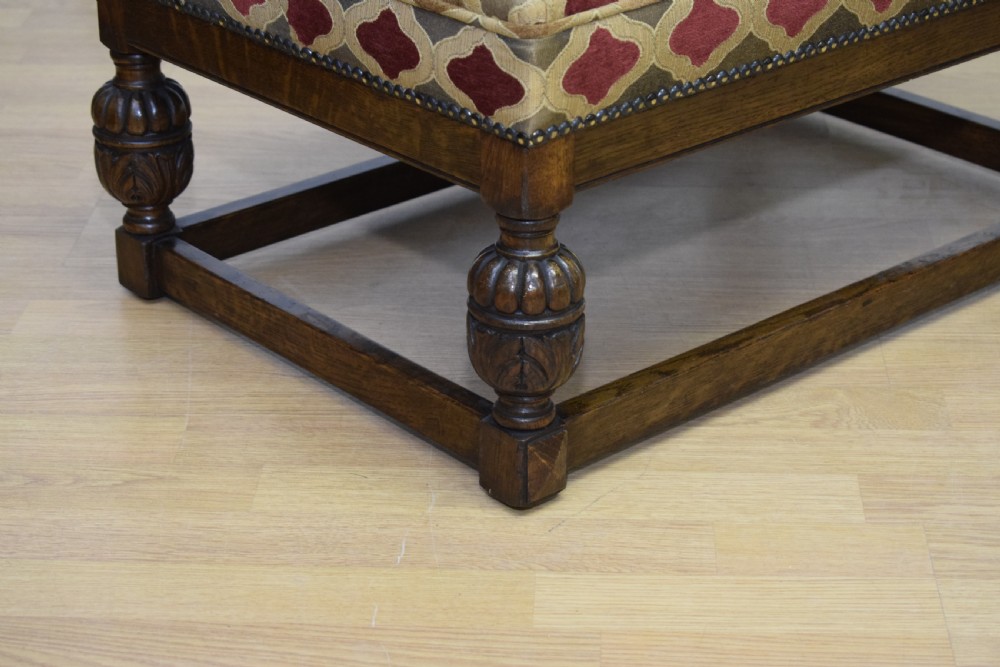 An antique carved oak stool with a geometric patterned upholstered seat, turned legs, and a perimeter wood stretcher. View IX