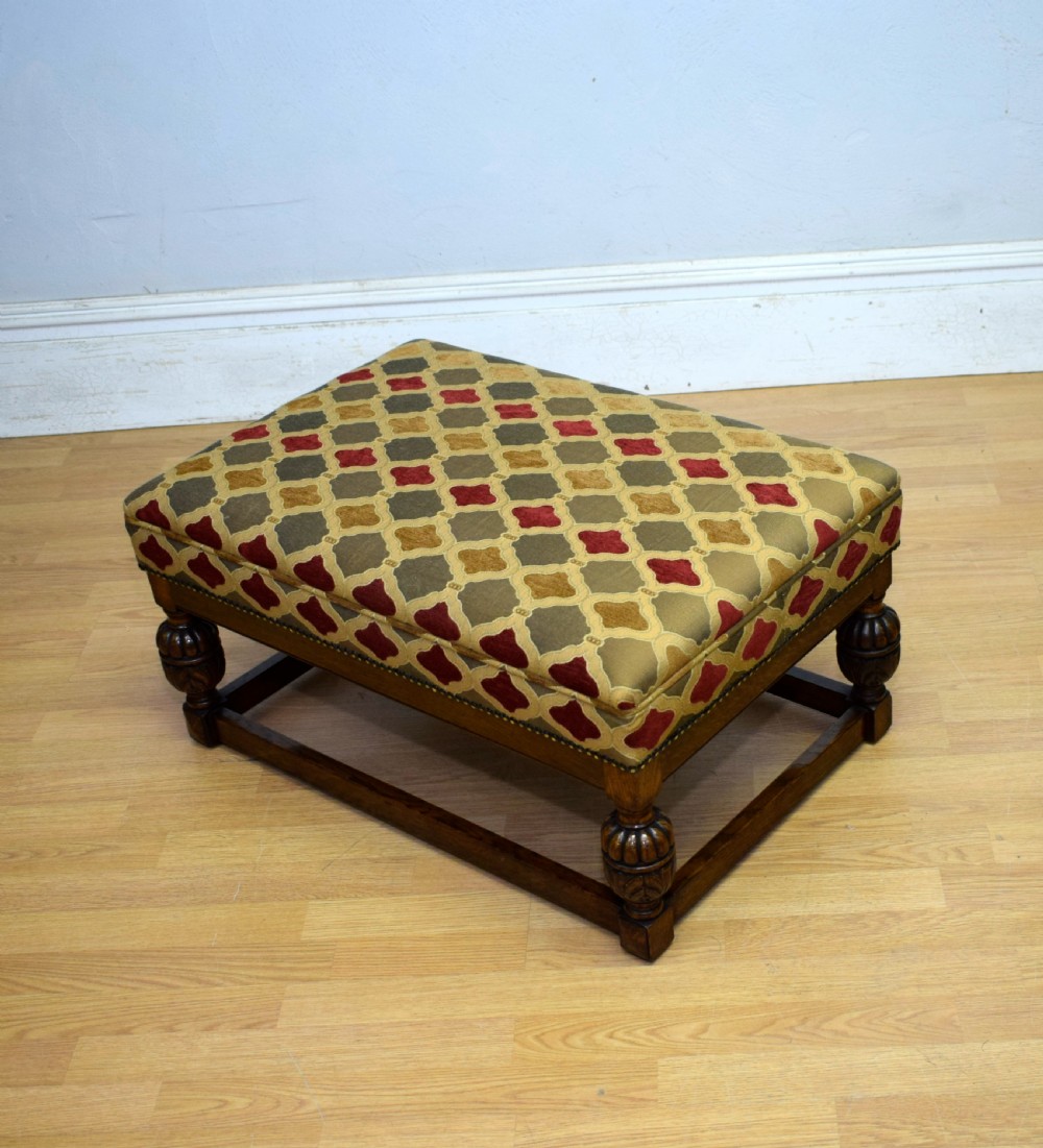 An antique carved oak stool with a geometric patterned upholstered seat, turned legs, and a perimeter wood stretcher. View XI