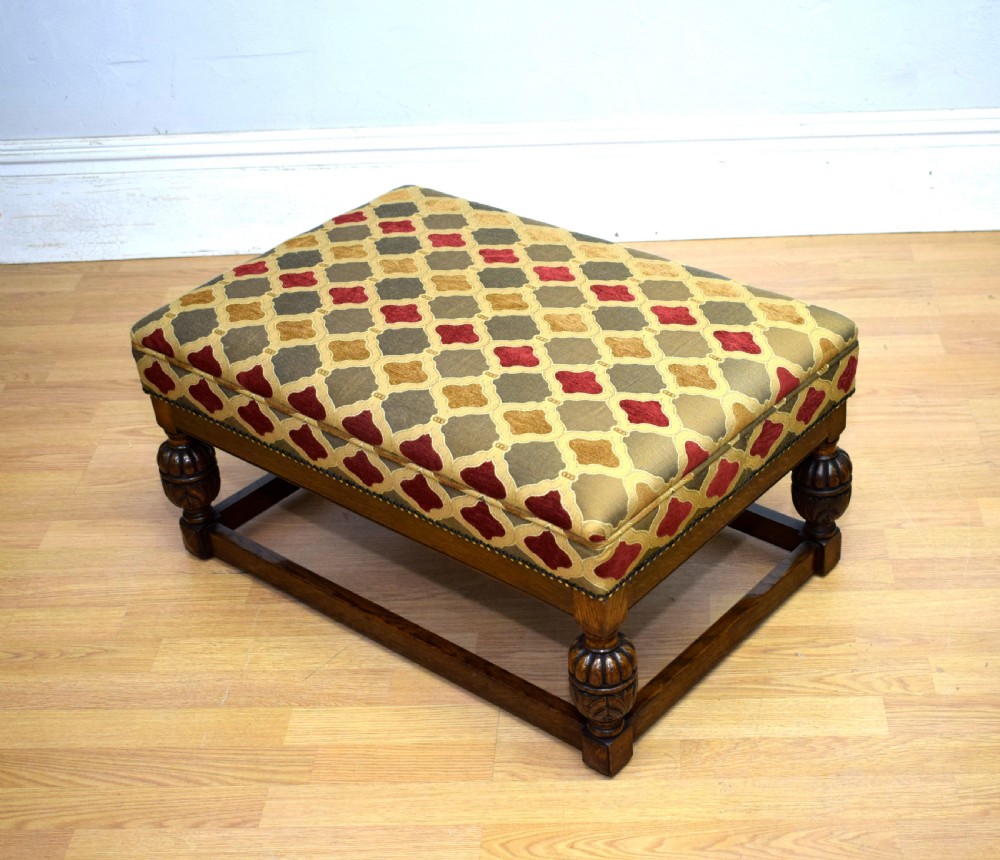 An antique carved oak stool with a geometric patterned upholstered seat, turned legs, and a perimeter wood stretcher. View XII