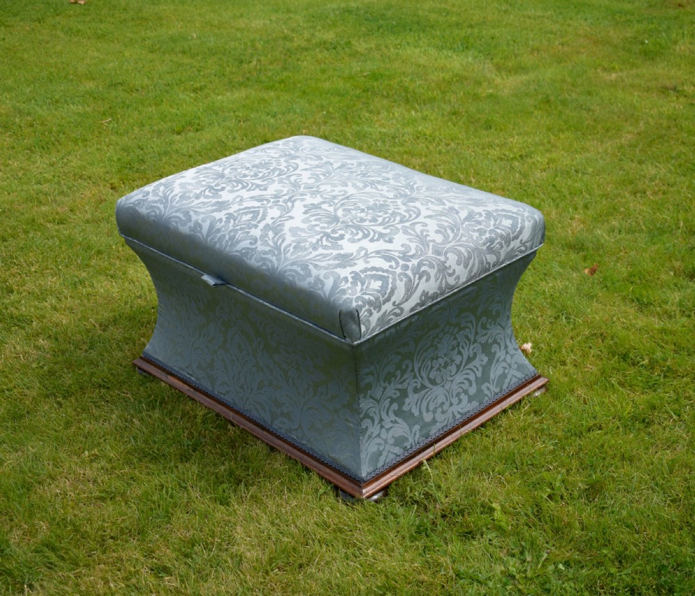 A Regency sarcophagus-shaped ottoman upholstered in blue and silver damask fabric set upon a rosewood plinth base.