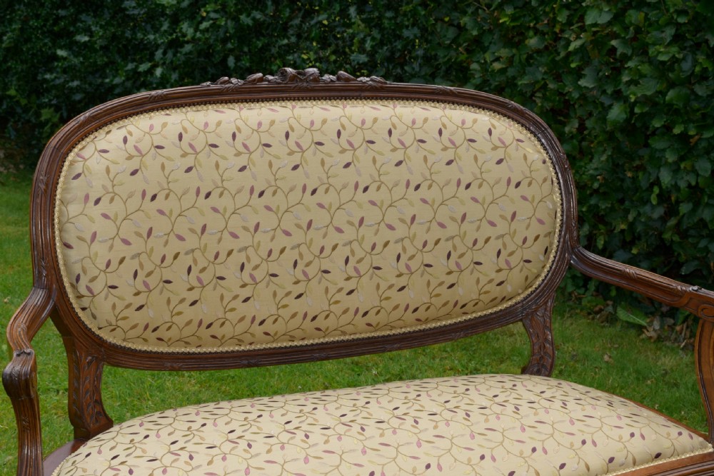 A French carved walnut settee with an oval upholstered backrest, turned fluted legs, and patterned textile upholstery. View III