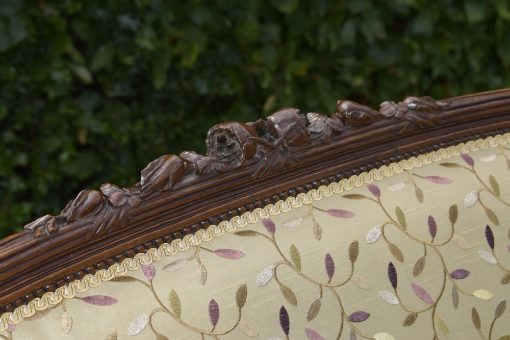 A French carved walnut settee with an oval upholstered backrest, turned fluted legs, and patterned textile upholstery. View VI