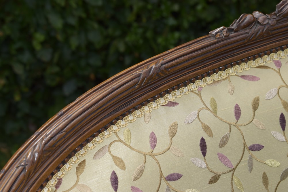 A French carved walnut settee with an oval upholstered backrest, turned fluted legs, and patterned textile upholstery. View VII