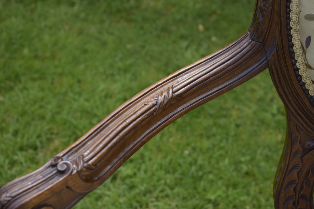 A French carved walnut settee with an oval upholstered backrest, turned fluted legs, and patterned textile upholstery. View IX