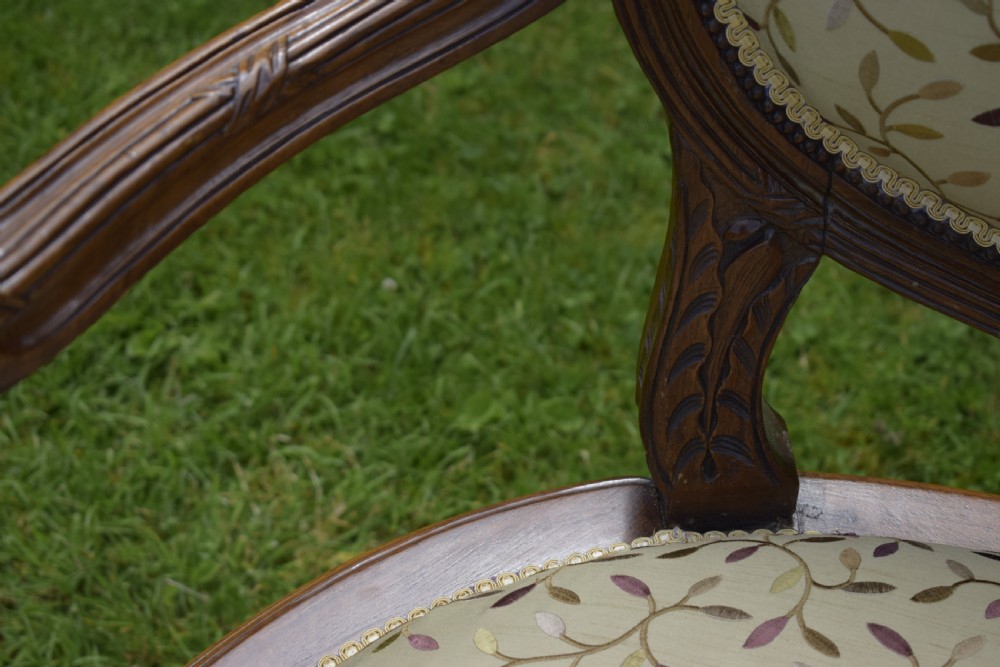 A French carved walnut settee with an oval upholstered backrest, turned fluted legs, and patterned textile upholstery. View X