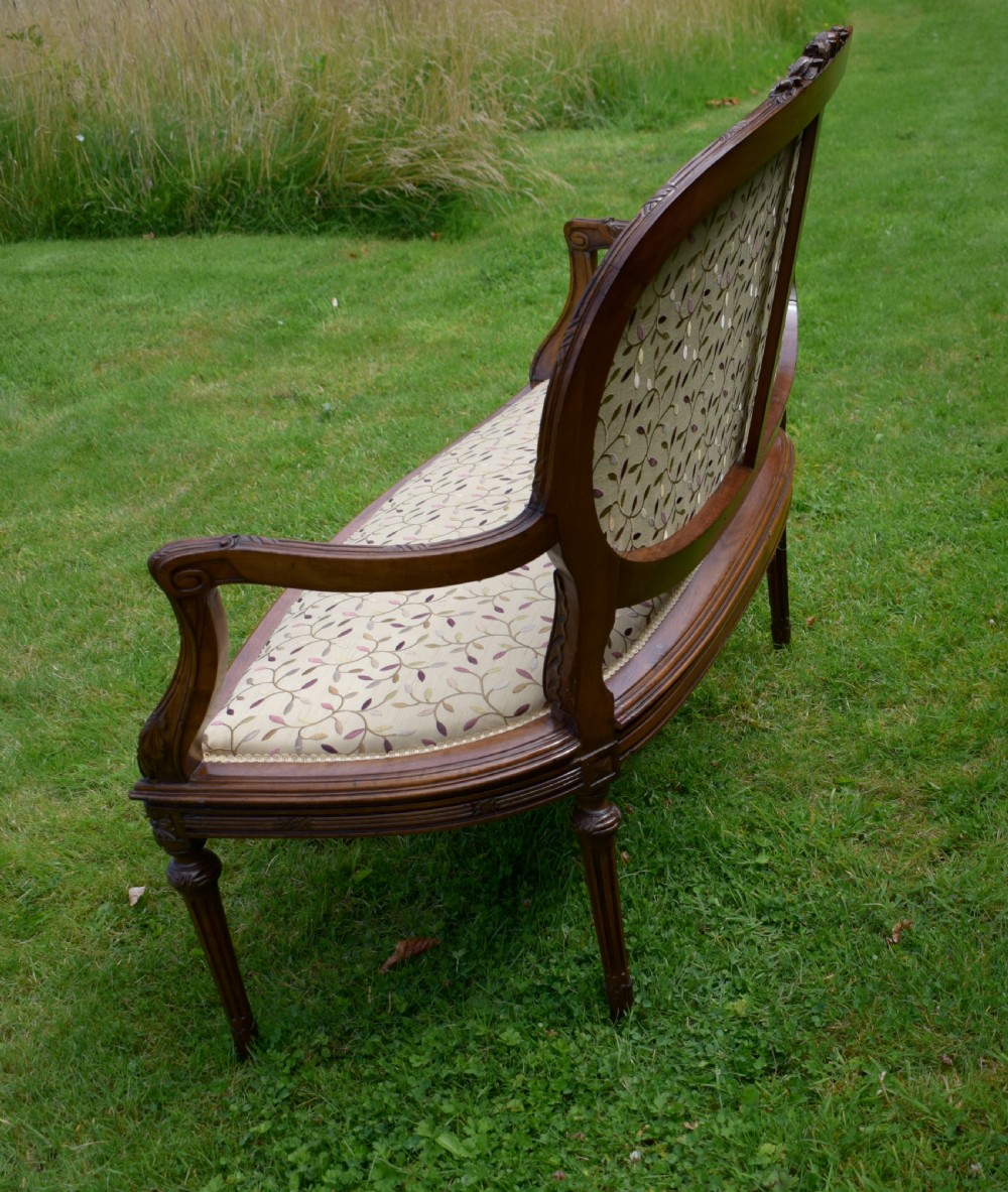 A French carved walnut settee with an oval upholstered backrest, turned fluted legs, and patterned textile upholstery. View XII