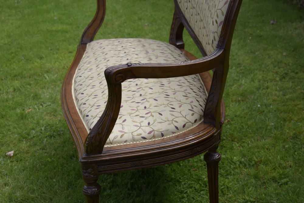 A French carved walnut settee with an oval upholstered backrest, turned fluted legs, and patterned textile upholstery. View XIV