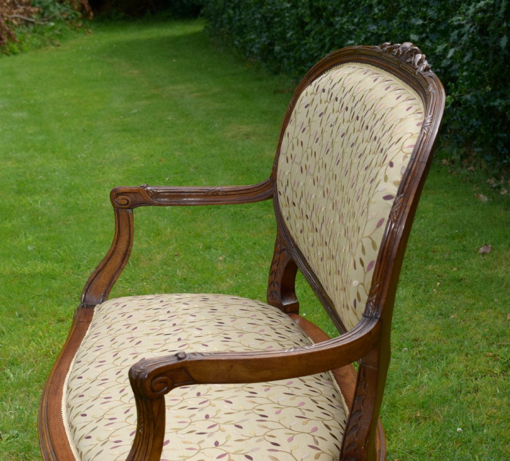 A French carved walnut settee with an oval upholstered backrest, turned fluted legs, and patterned textile upholstery. View XV
