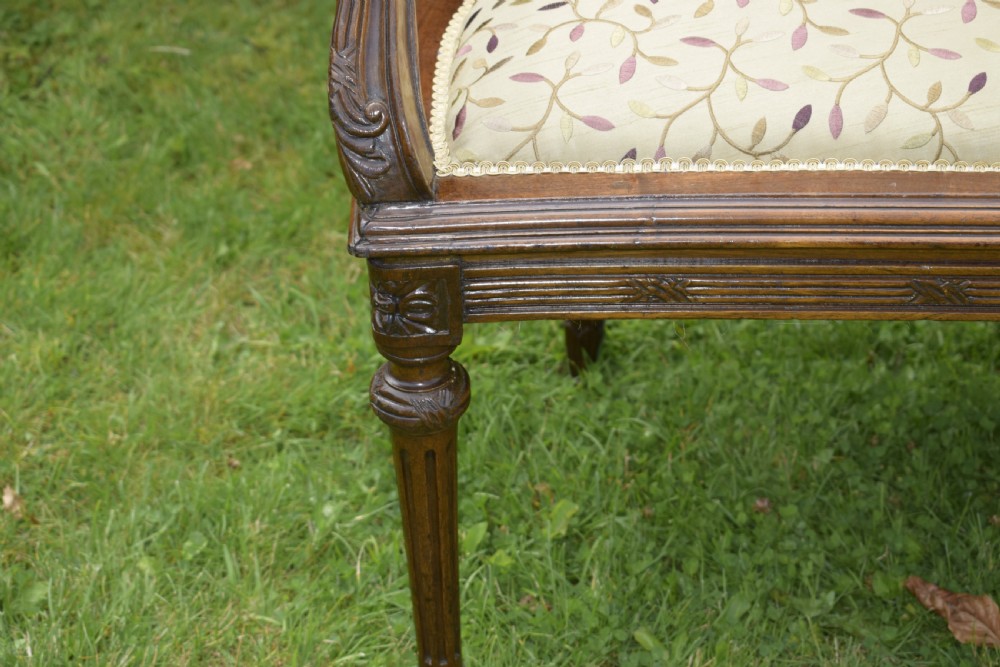 A French carved walnut settee with an oval upholstered backrest, turned fluted legs, and patterned textile upholstery. View XVI
