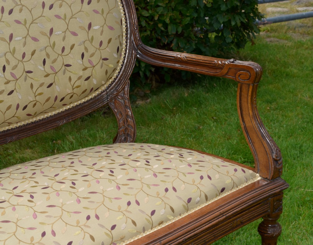 A French carved walnut settee with an oval upholstered backrest, turned fluted legs, and patterned textile upholstery. View XVII