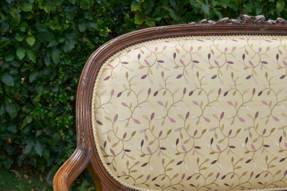 A French carved walnut settee with an oval upholstered backrest, turned fluted legs, and patterned textile upholstery. View XVIII