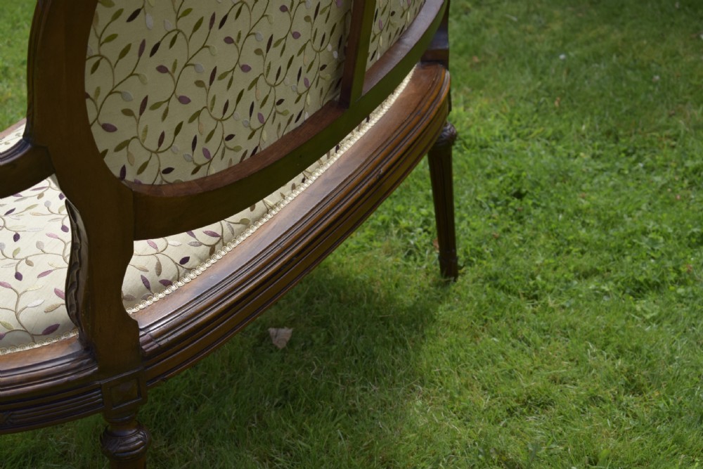 A French carved walnut settee with an oval upholstered backrest, turned fluted legs, and patterned textile upholstery. View XIX
