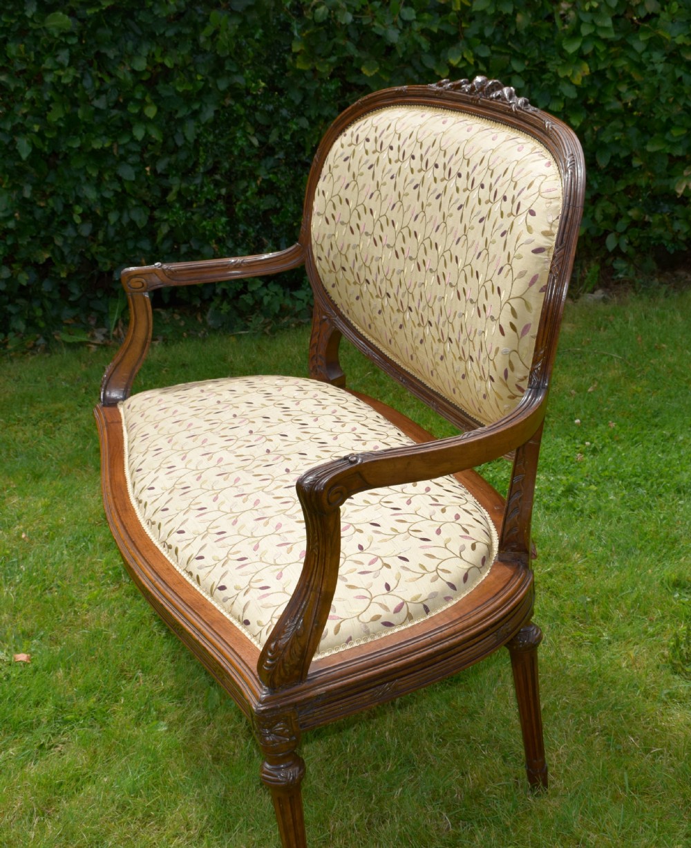 A French carved walnut settee with an oval upholstered backrest, turned fluted legs, and patterned textile upholstery. View XX