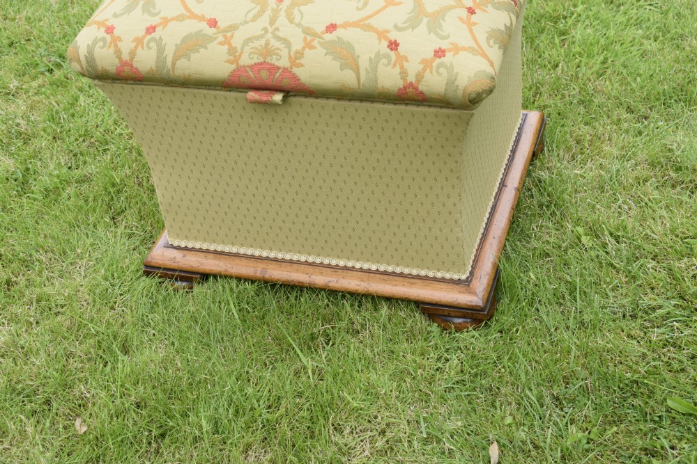 A square William IV upholstered ottoman work box featuring a gold and red floral patterned lid, flared fabric body, and a mahogany plinth base. View V