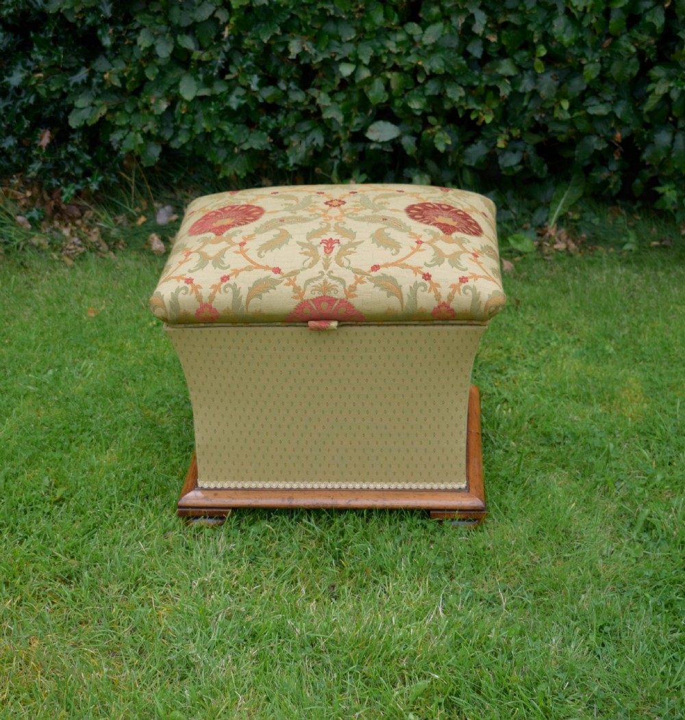 A square William IV upholstered ottoman work box featuring a gold and red floral patterned lid, flared fabric body, and a mahogany plinth base. View VII