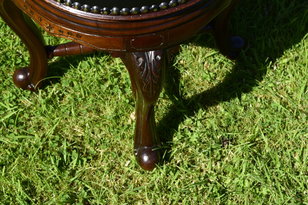A Victorian walnut piano stool with a circular black leather upholstered swivel seat resting on four carved cabriole legs. View XIV