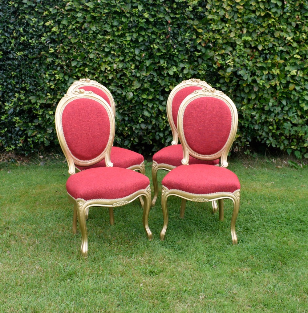 A set of four French-style dining chairs featuring gold-painted frames with carved oval backs and red woven fabric upholstery. View II