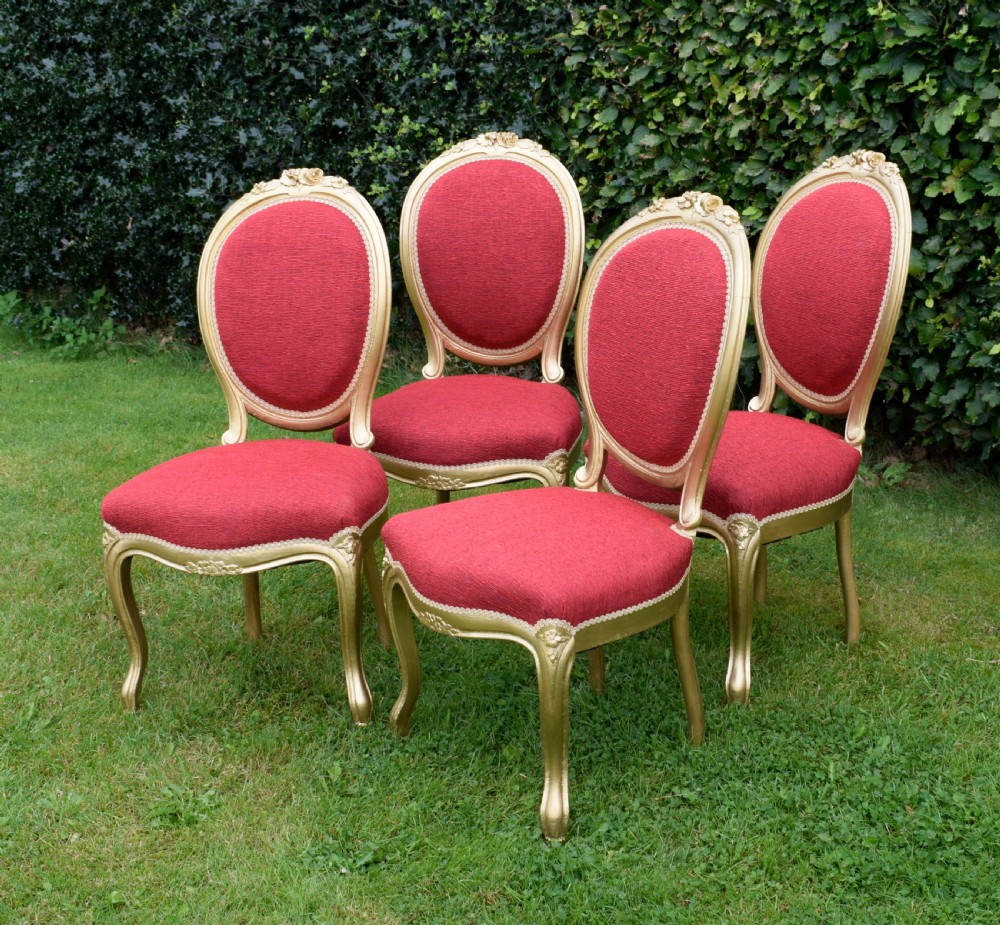 A set of four French-style dining chairs featuring gold-painted frames with carved oval backs and red woven fabric upholstery. View VIII