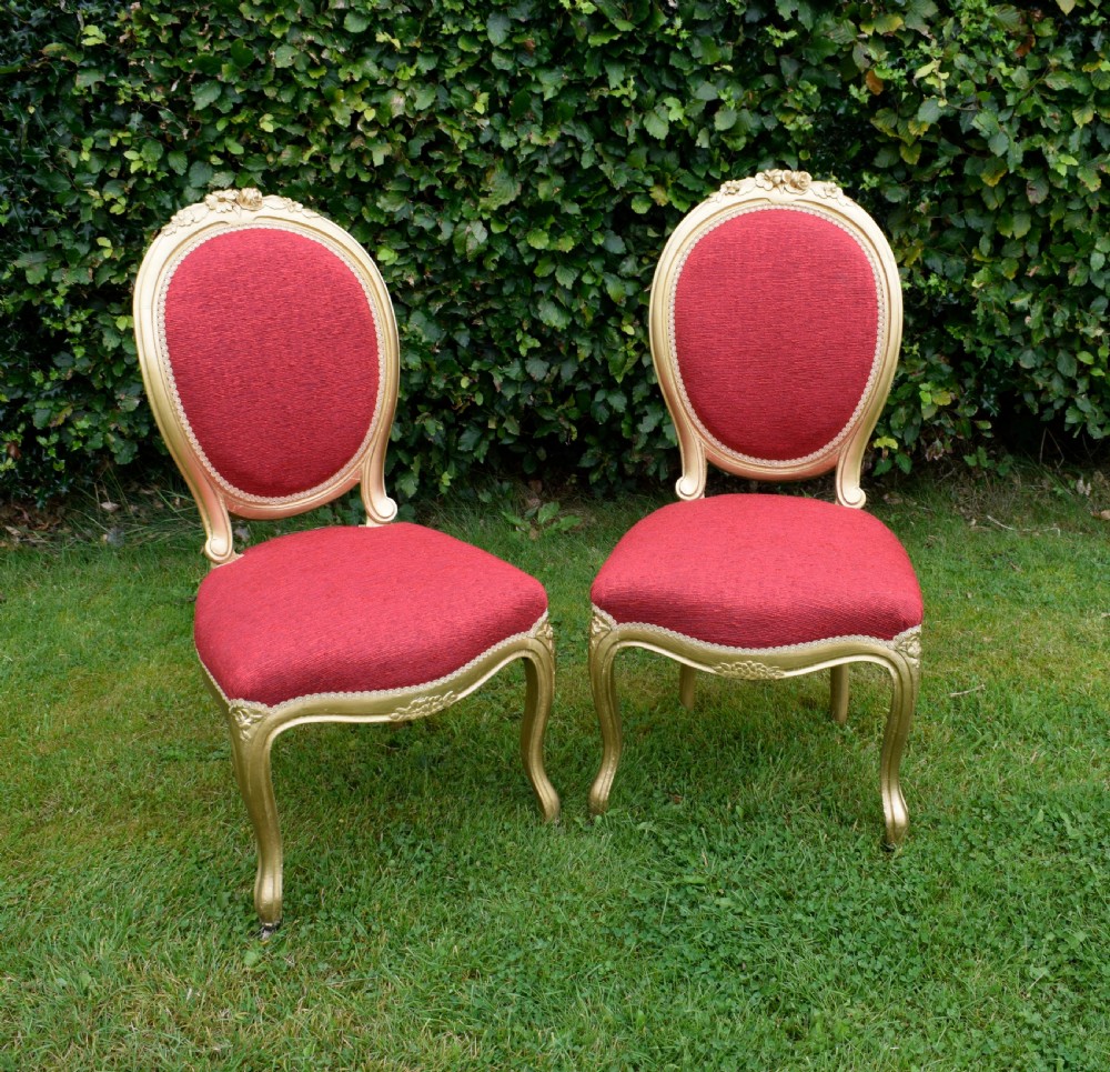 A set of four French-style dining chairs featuring gold-painted frames with carved oval backs and red woven fabric upholstery. View XIII
