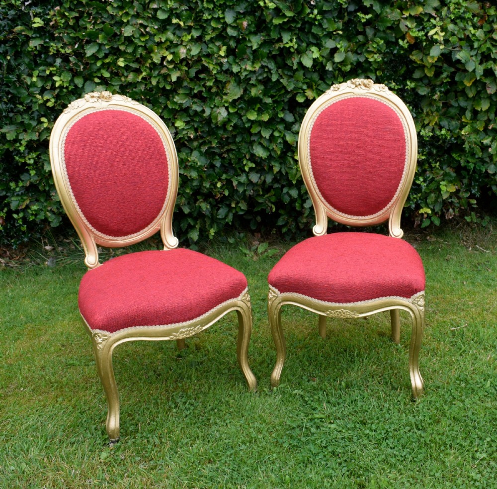 A set of four French-style dining chairs featuring gold-painted frames with carved oval backs and red woven fabric upholstery. View XIV