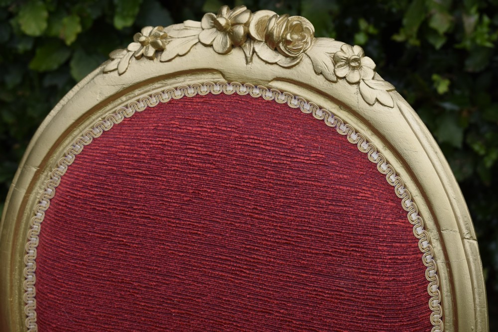 A set of four French-style dining chairs featuring gold-painted frames with carved oval backs and red woven fabric upholstery. View XIX