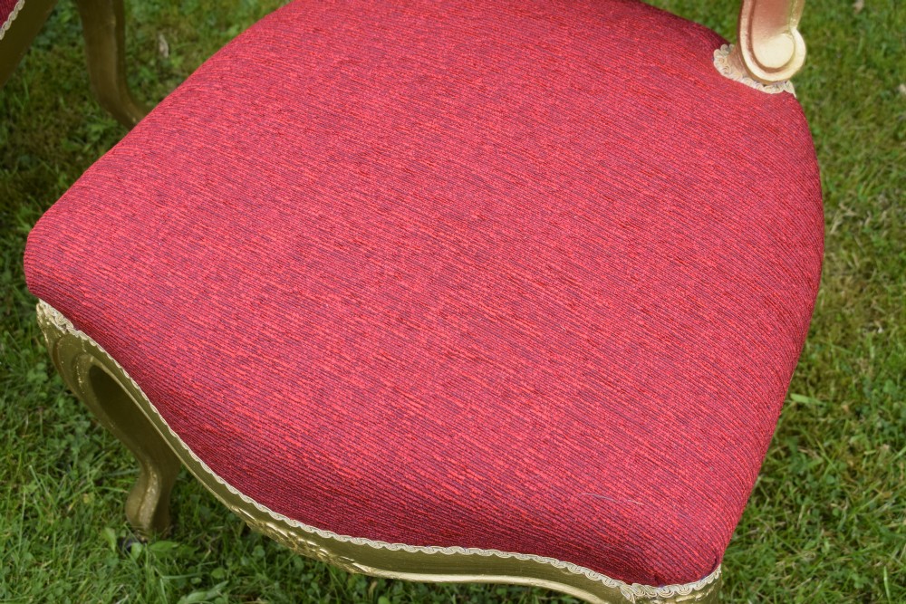 A set of four French-style dining chairs featuring gold-painted frames with carved oval backs and red woven fabric upholstery. View XX