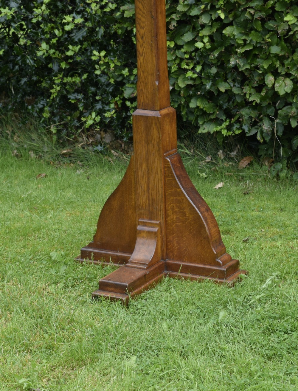 An early 20th-century solid oak floor-standing lectern featuring an angled book rest above a central column supported by a stepped cruciform base. View VIII