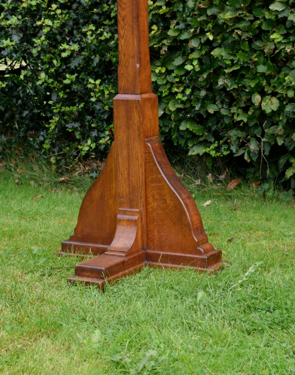 An early 20th-century solid oak floor-standing lectern featuring an angled book rest above a central column supported by a stepped cruciform base. View XI