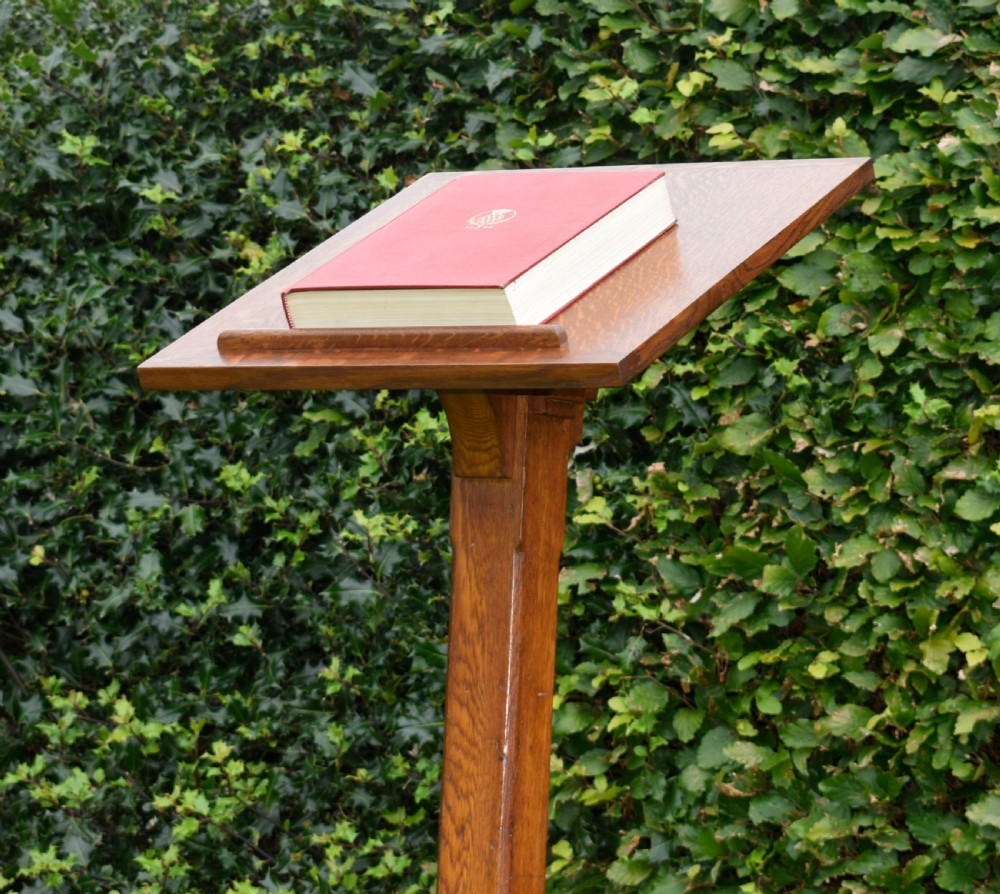 An early 20th-century solid oak floor-standing lectern featuring an angled book rest above a central column supported by a stepped cruciform base. View XII