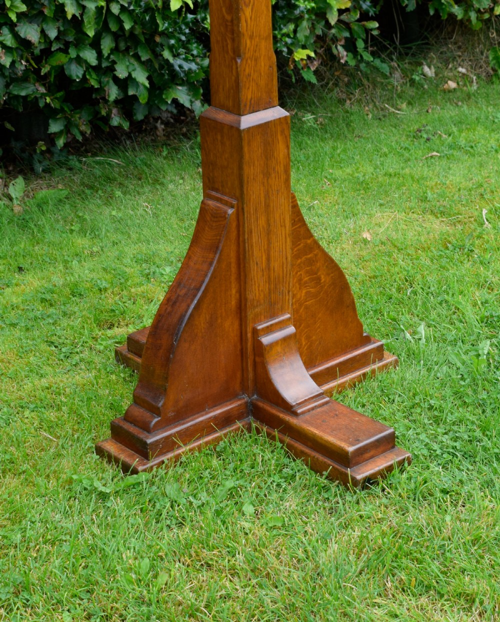 An early 20th-century solid oak floor-standing lectern featuring an angled book rest above a central column supported by a stepped cruciform base. View XIV