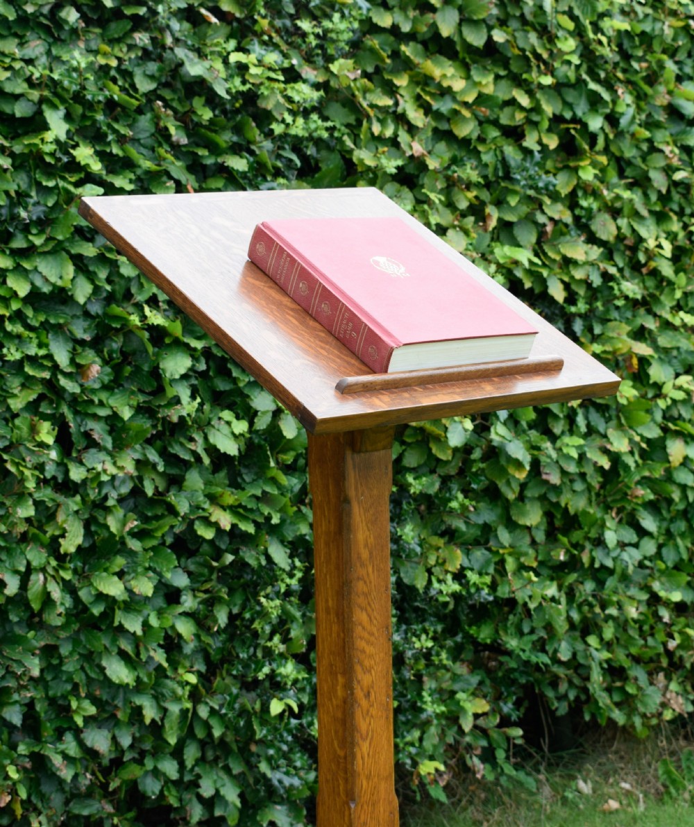 An early 20th-century solid oak floor-standing lectern featuring an angled book rest above a central column supported by a stepped cruciform base. View XV